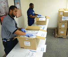Dandre Wallace (left), materials specialist, and Sean Brunson, coordinator of surgical supply, pack up surgical gloves, needles, syringes, surgical sponges, skin staplers and other trauma medical equipment being sent to Barzilai Hospital, the  sister hospital of Sinai Medical Center in Baltimore, located in Ashkelon, Baltimore’s sister city. (Melissa Gerr)